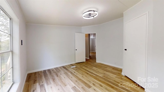unfurnished bedroom featuring multiple windows, light wood-style floors, and baseboards