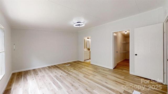 interior space with baseboards, light wood-style flooring, and connected bathroom