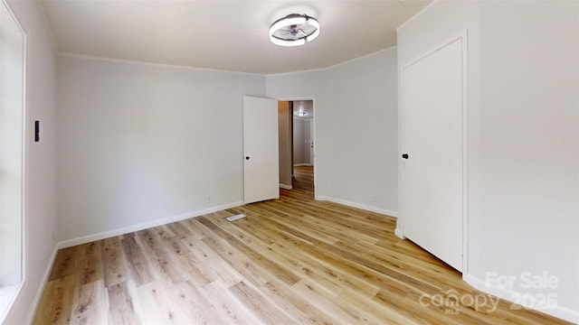 unfurnished bedroom featuring baseboards, light wood-style floors, and crown molding