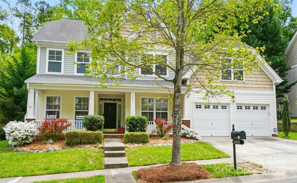 12531 Morning Creek Ln, Charlotte, NC 28214 - view of front of home featuring a front lawn, an attached garage, driveway, a porch, and roof with shingles