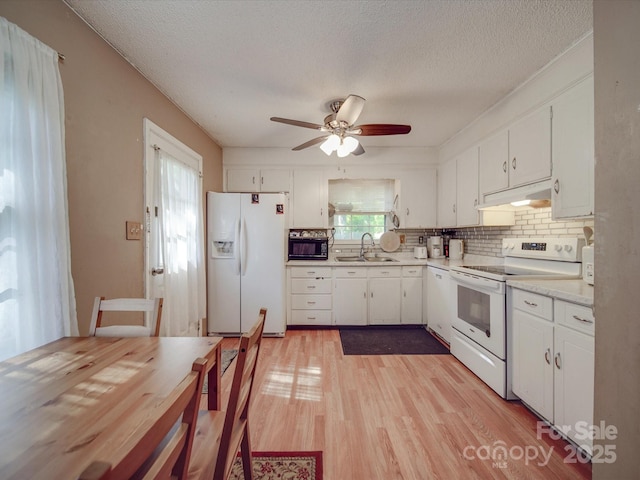 6820 Elm Forest Dr, Charlotte, NC 28212 - kitchen featuring white appliances, white cabinetry, under cabinet range hood, light countertops, and a sink