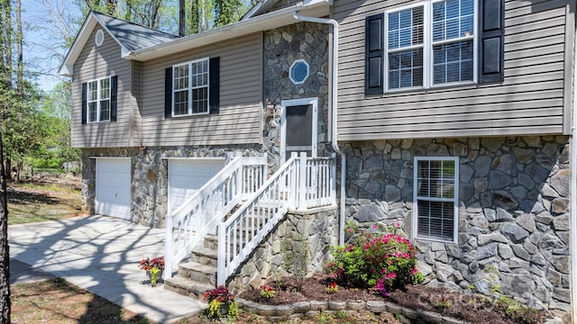 view of front facade with an attached garage, driveway, and stone siding