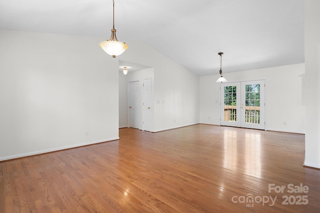 interior space featuring baseboards, light wood-type flooring, and lofted ceiling