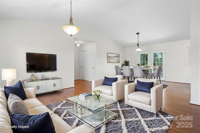 living area featuring baseboards, vaulted ceiling, and wood finished floors