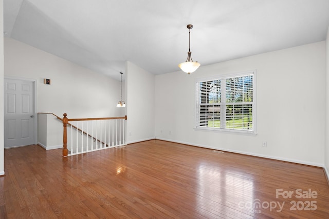 empty room with baseboards, wood finished floors, and lofted ceiling