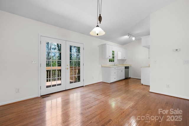 unfurnished dining area featuring french doors, visible vents, a sink, baseboards, and light wood-style floors