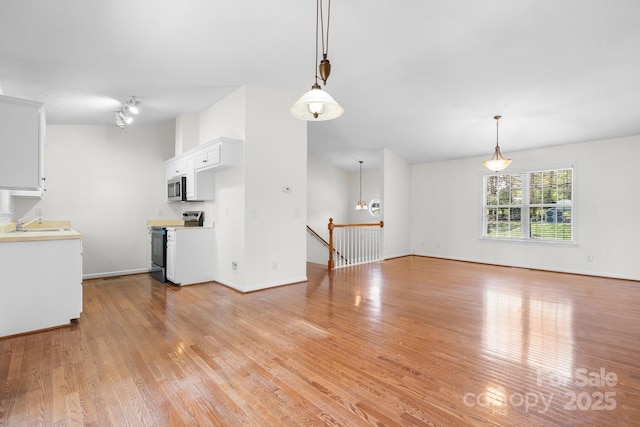 unfurnished living room featuring baseboards, a sink, and light wood finished floors