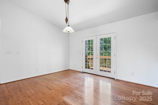 unfurnished room featuring baseboards, wood finished floors, and french doors