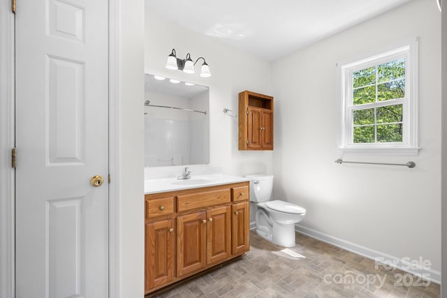 full bath featuring walk in shower, baseboards, vanity, brick patterned floor, and toilet