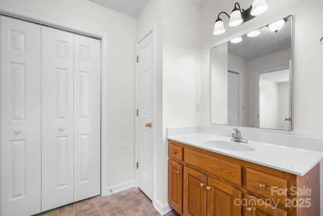 bathroom featuring a closet, baseboards, and vanity