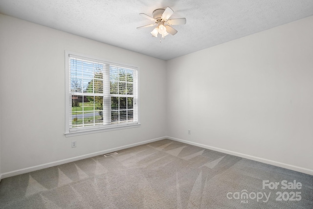 carpeted spare room featuring a ceiling fan, baseboards, visible vents, and a textured ceiling