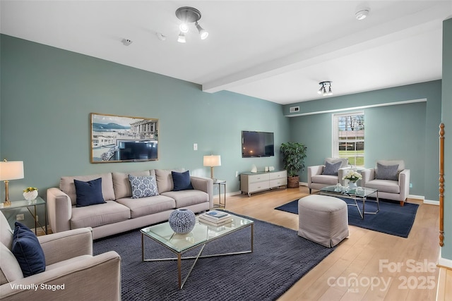 living area featuring baseboards, beam ceiling, wood finished floors, and visible vents