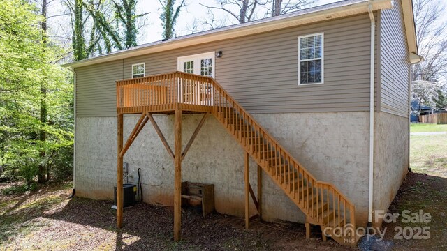 rear view of property featuring cooling unit, a wooden deck, and stairs