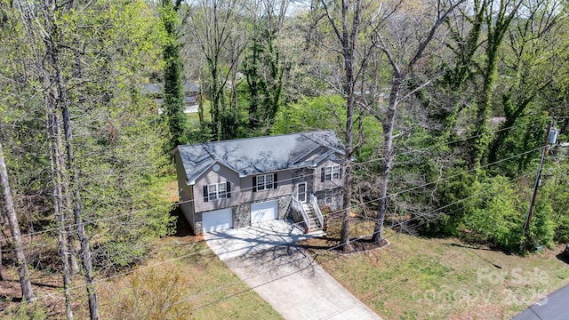 view of front of house with driveway, a wooded view, stairs, and a garage