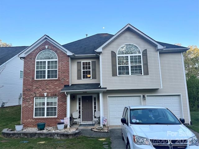 traditional-style house with aphalt driveway, brick siding, and an attached garage