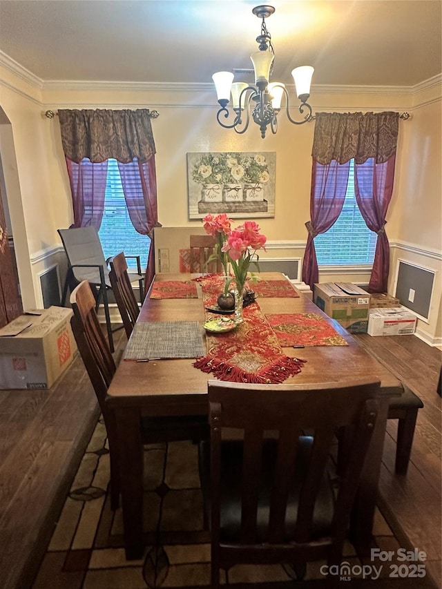 dining space featuring a chandelier, a wealth of natural light, ornamental molding, and wood finished floors