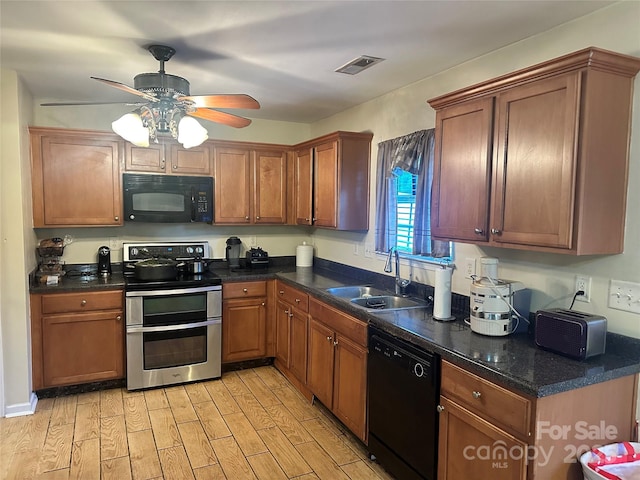 kitchen featuring visible vents, a sink, ceiling fan, black appliances, and light wood finished floors