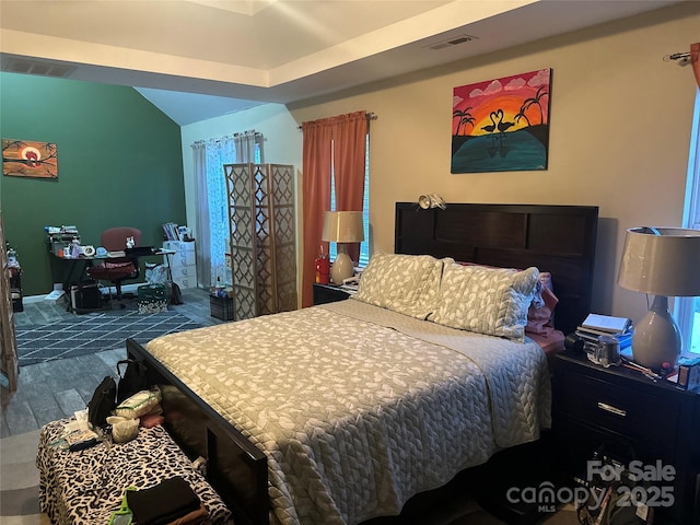 bedroom with wood finished floors, baseboards, vaulted ceiling, and visible vents