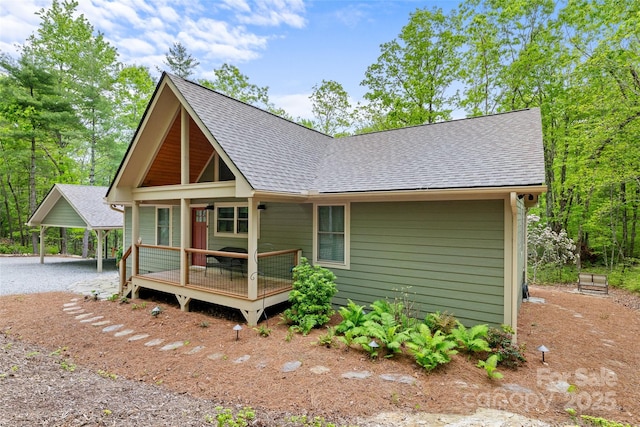 view of front of property featuring a shingled roof and dirt driveway