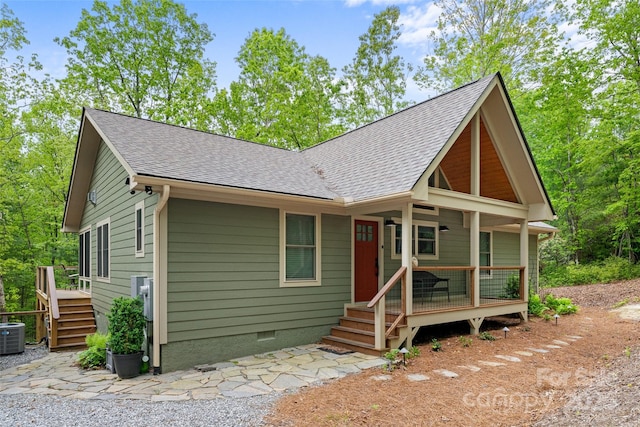 view of front facade featuring a shingled roof, crawl space, cooling unit, and covered porch