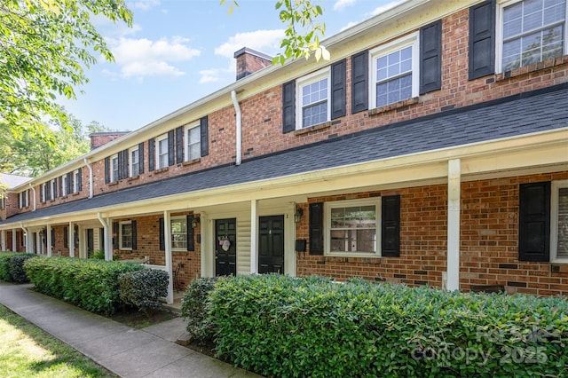 view of front of house featuring a porch, roof with shingles, and a chimney