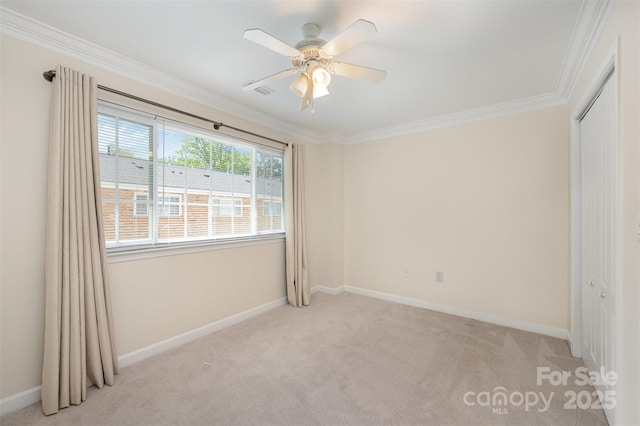 empty room with baseboards, light colored carpet, crown molding, and ceiling fan