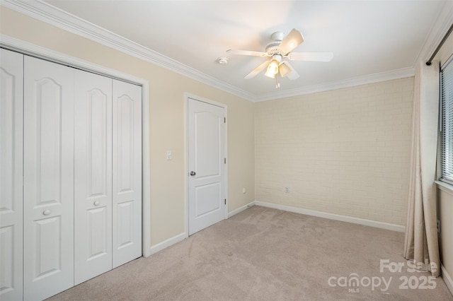 unfurnished bedroom featuring a closet, baseboards, brick wall, crown molding, and light colored carpet