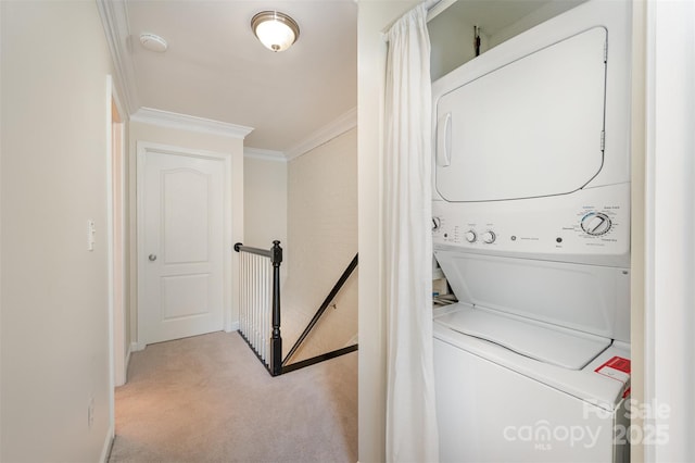 laundry area with baseboards, stacked washer and clothes dryer, laundry area, crown molding, and carpet floors