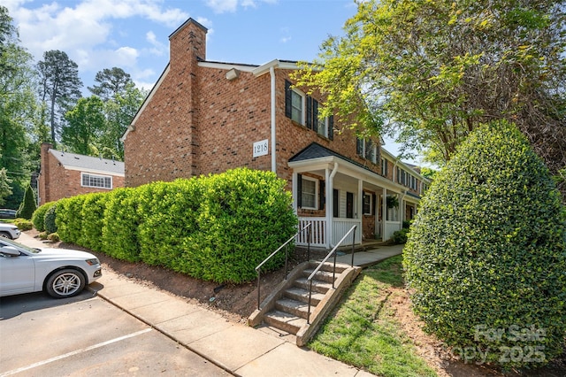 view of property exterior featuring brick siding, a porch, and uncovered parking
