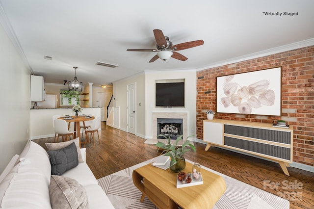 living room with visible vents, baseboards, wood finished floors, and ornamental molding