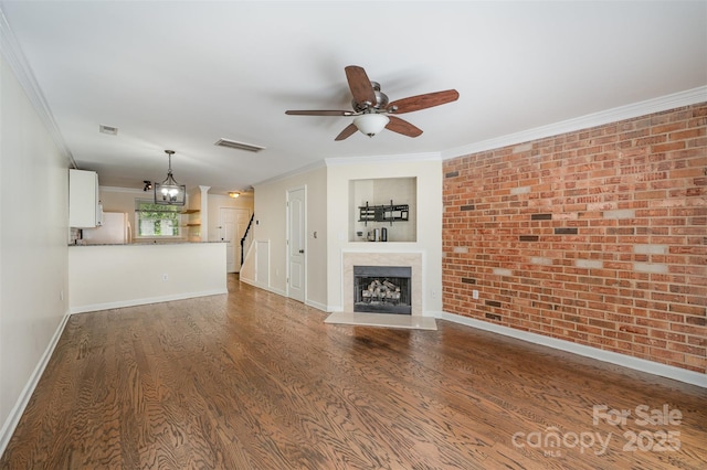 unfurnished living room with visible vents, ceiling fan with notable chandelier, ornamental molding, and wood finished floors