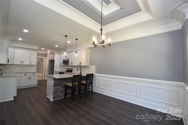 6519 Pargo Rd, Charlotte, NC 28216 - kitchen with a notable chandelier, stainless steel appliances, a peninsula, a kitchen bar, and ornamental molding