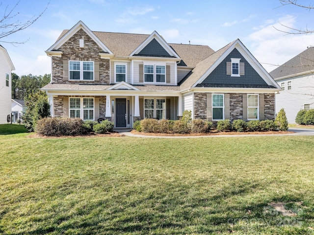 craftsman-style home featuring a shingled roof, stone siding, and a front lawn