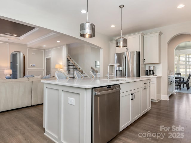 kitchen featuring arched walkways, a sink, open floor plan, dark wood-style flooring, and appliances with stainless steel finishes