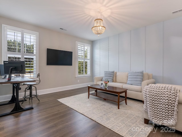 living area with dark wood-type flooring, visible vents, baseboards, and an inviting chandelier