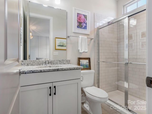 full bathroom with a shower stall, vanity, and toilet
