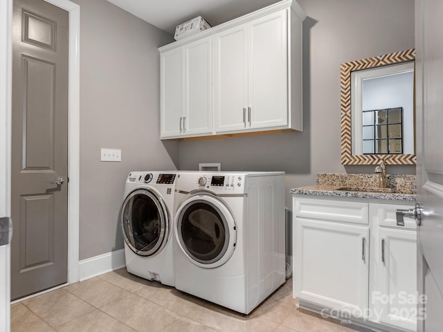 laundry area featuring baseboards, light tile patterned floors, washing machine and dryer, cabinet space, and a sink