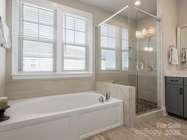 full bathroom featuring vanity, a bath, a stall shower, and wood finished floors