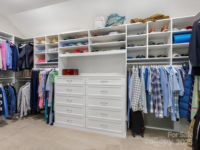 walk in closet with light colored carpet and lofted ceiling