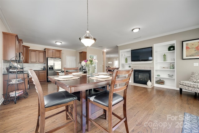 985 Angelica Ln, Tega Cay, SC 29708 - dining space with ornamental molding, built in shelves, light wood finished floors, and a fireplace
