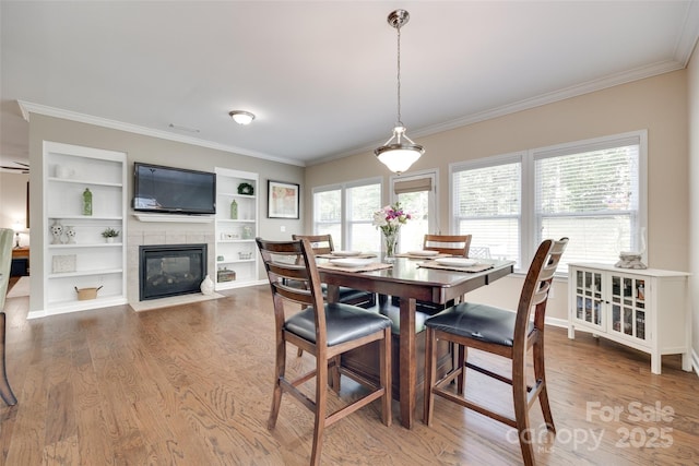 985 Angelica Ln, Tega Cay, SC 29708 - dining area with crown molding, wood finished floors, built in shelves, and a tile fireplace