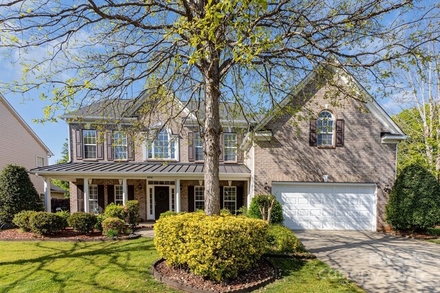 6941 Augustine Way, Charlotte, NC 28270 - view of front of house featuring brick siding, an attached garage, a front lawn, driveway, and a standing seam roof