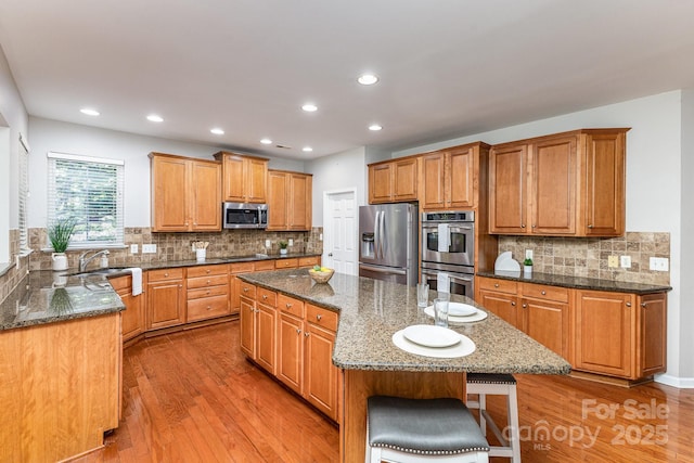 6941 Augustine Way, Charlotte, NC 28270 - kitchen featuring stainless steel appliances, a center island, dark stone counters, recessed lighting, and light wood-type flooring