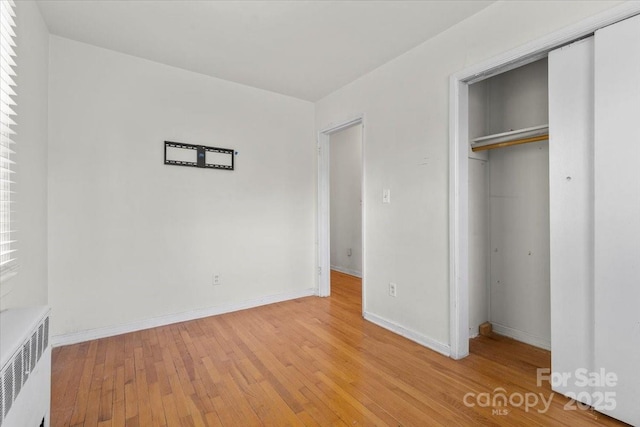 343 Wakefield Dr Unit C, Charlotte, NC 28209 - unfurnished bedroom featuring radiator, a closet, light wood finished floors, and baseboards