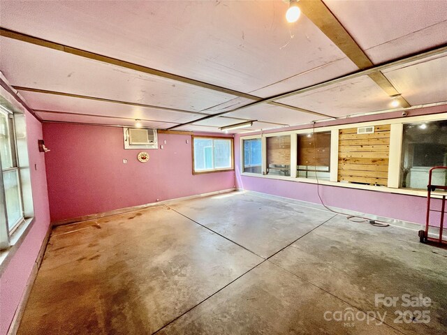 below grade area with visible vents, an AC wall unit, and baseboards