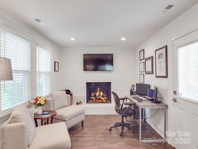 office featuring visible vents, plenty of natural light, wood finished floors, and a brick fireplace