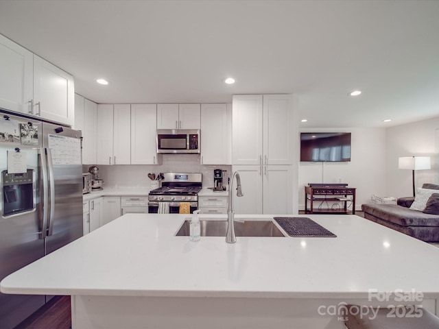 kitchen with appliances with stainless steel finishes, a sink, white cabinetry, and light countertops