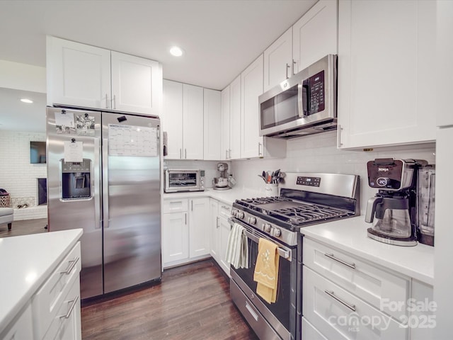 kitchen with dark wood finished floors, decorative backsplash, appliances with stainless steel finishes, and light countertops