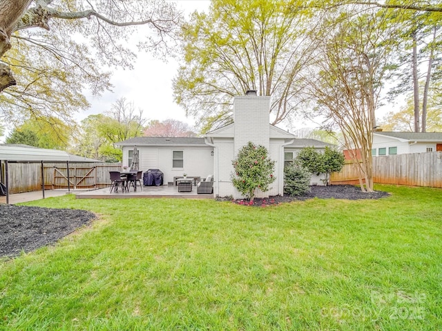rear view of property featuring a fenced backyard, a chimney, a yard, and a patio area