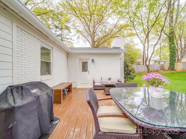 wooden terrace featuring outdoor dining area, fence, grilling area, and a lawn